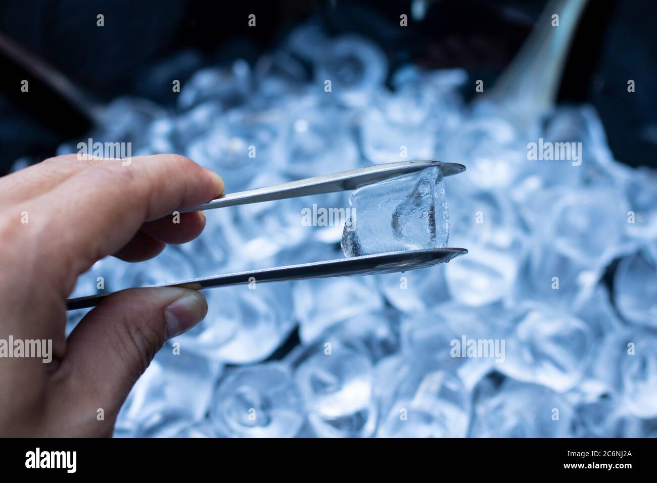 Mann, der die Eisklemme hält. Viel Eiswürfel Hintergrund. Nahaufnahme. Stockfoto