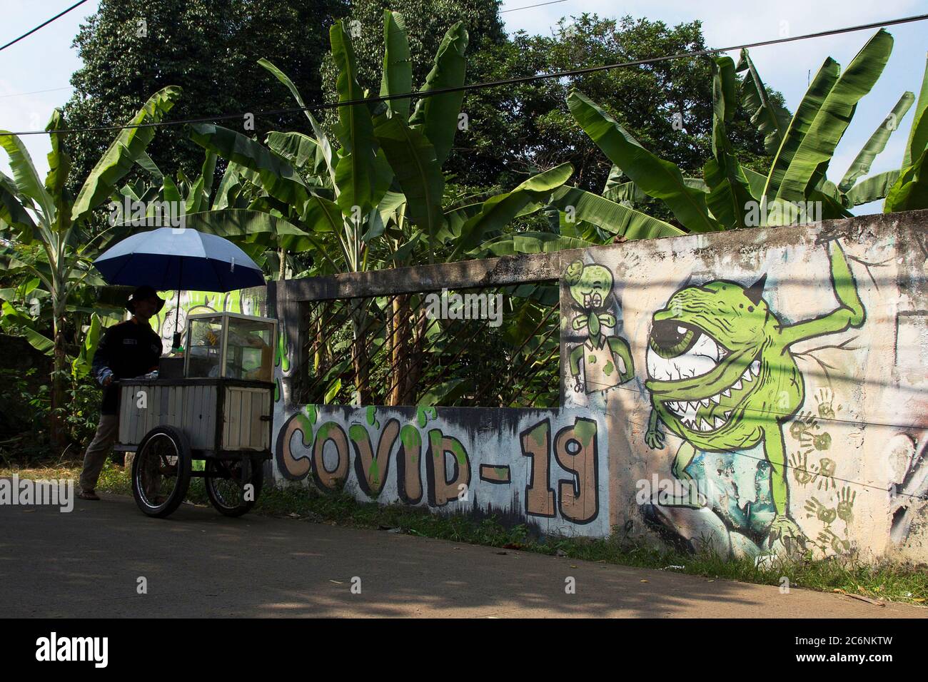 Depok, Indonesien. Juli 2020. Ein Händler geht in der Nähe des Corona-Virus-Wandbildes (Covid-19) in Cimanggis, Depok, West Java, Indonesien, Samstag, 11. Juli 2020. (Foto von Yogi Aron Sidabariba/INA Photo Agency/Sipa USA) Quelle: SIPA USA/Alamy Live News Stockfoto