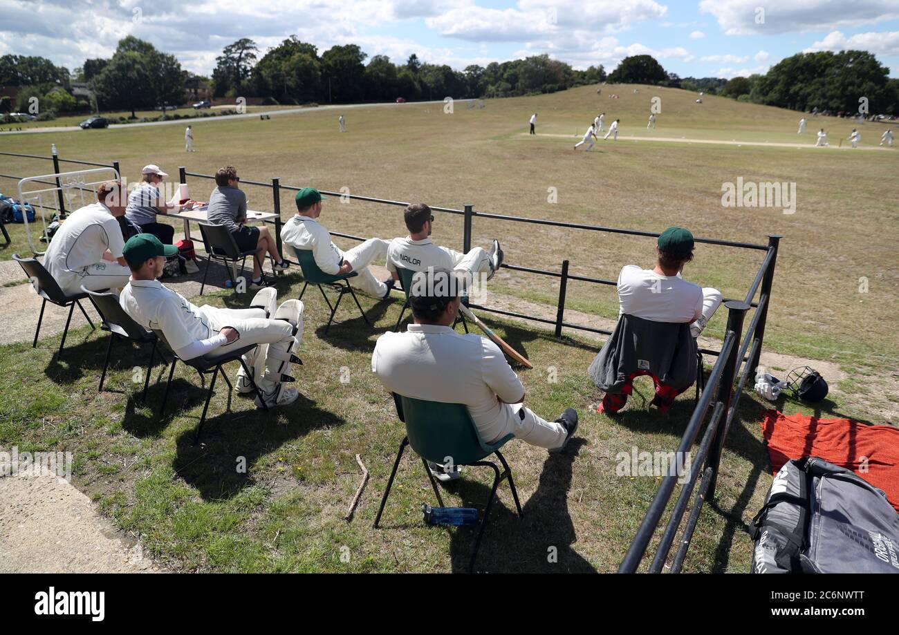 Spieler distanzieren sich sozial außerhalb des Clubhauses, während sie das Freundschaftsspiel zwischen Lyndhurst & Ashurst CC Cricket Club und Sway Cricket Club in Boltons Bench, in der Nähe von Lyndhurst, beobachten. Stockfoto