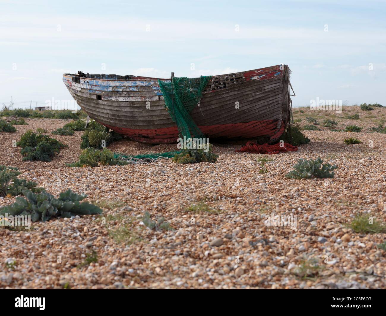 Der Rumpf eines verlassenen Fischerbootes am Dungeness Beach, einer Landzunge an der Küste von Kent, England, bildete weitgehend einen Kiesstrand. Stockfoto