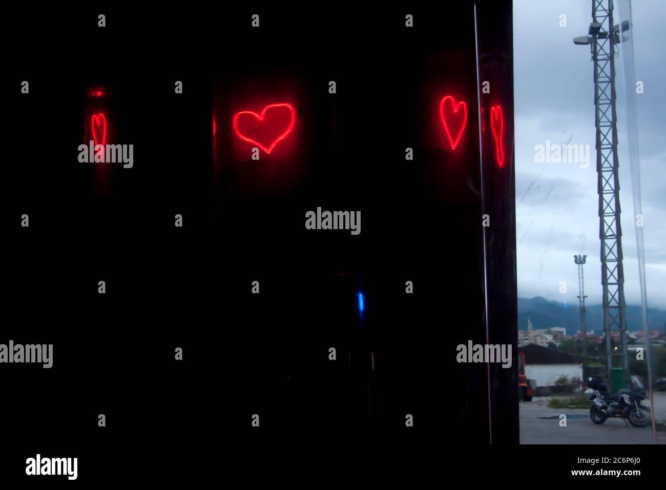 Neonlicht leuchtend rote Herzreflexionen auf dem transparenten Kunststoffschirm Stockfoto
