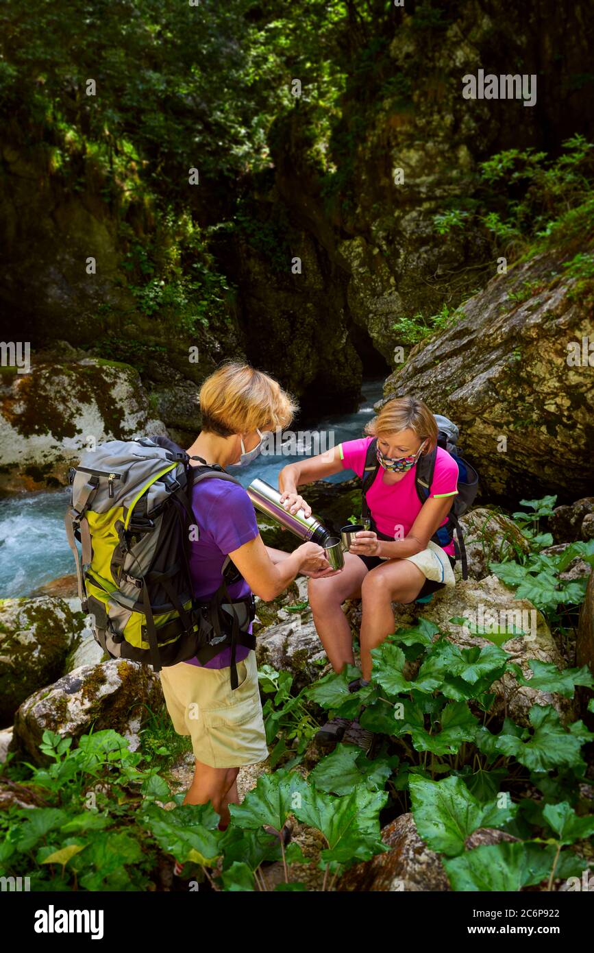 Zwei Frauen befolgen die Sicherheitsempfehlungen bei Outdoor-Aktivitäten. Trekking, covid-19, sichere Maske. Stockfoto