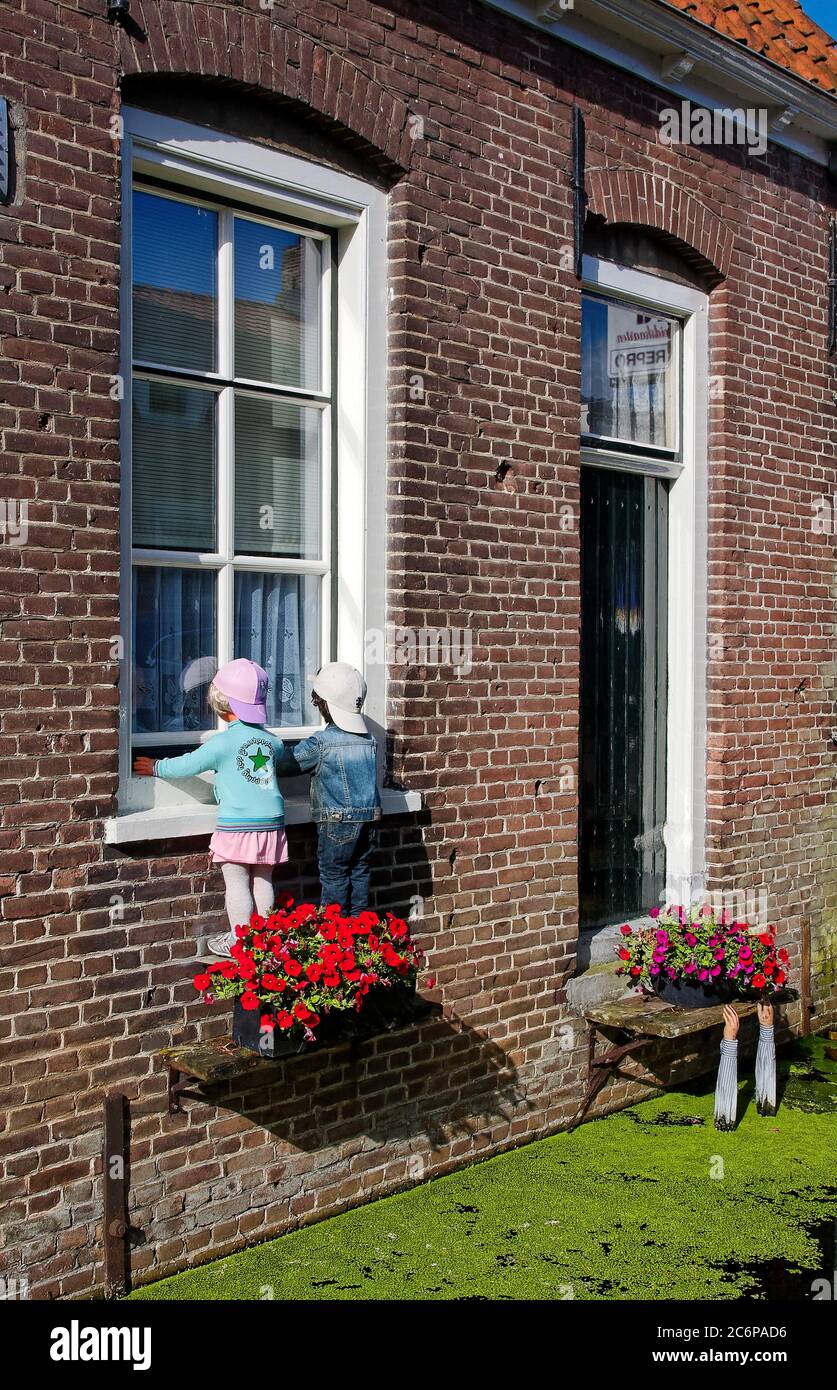 Manequins Blick ins Fenster, Junge, Mädchen, Kinder, Blumenkasten, Kanal  grün mit Algen, gefälschte Arme hängen auf Regal, reichen aus Wasser,  humorvoll Stockfotografie - Alamy