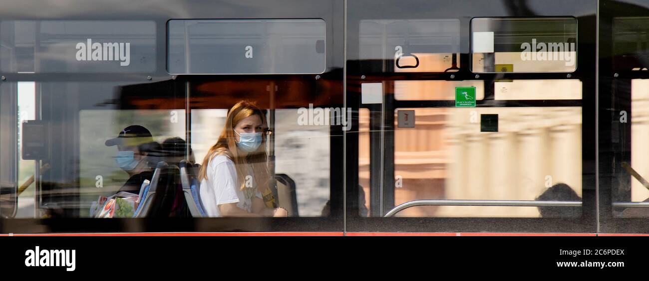 Belgrad, Serbien - 4. Juli 2020: Eine Jugendliche Frau mit Gesichtsmaske, die auf dem Fensterplatz eines öffentlichen Nahverkehrs-Busses reitet Stockfoto