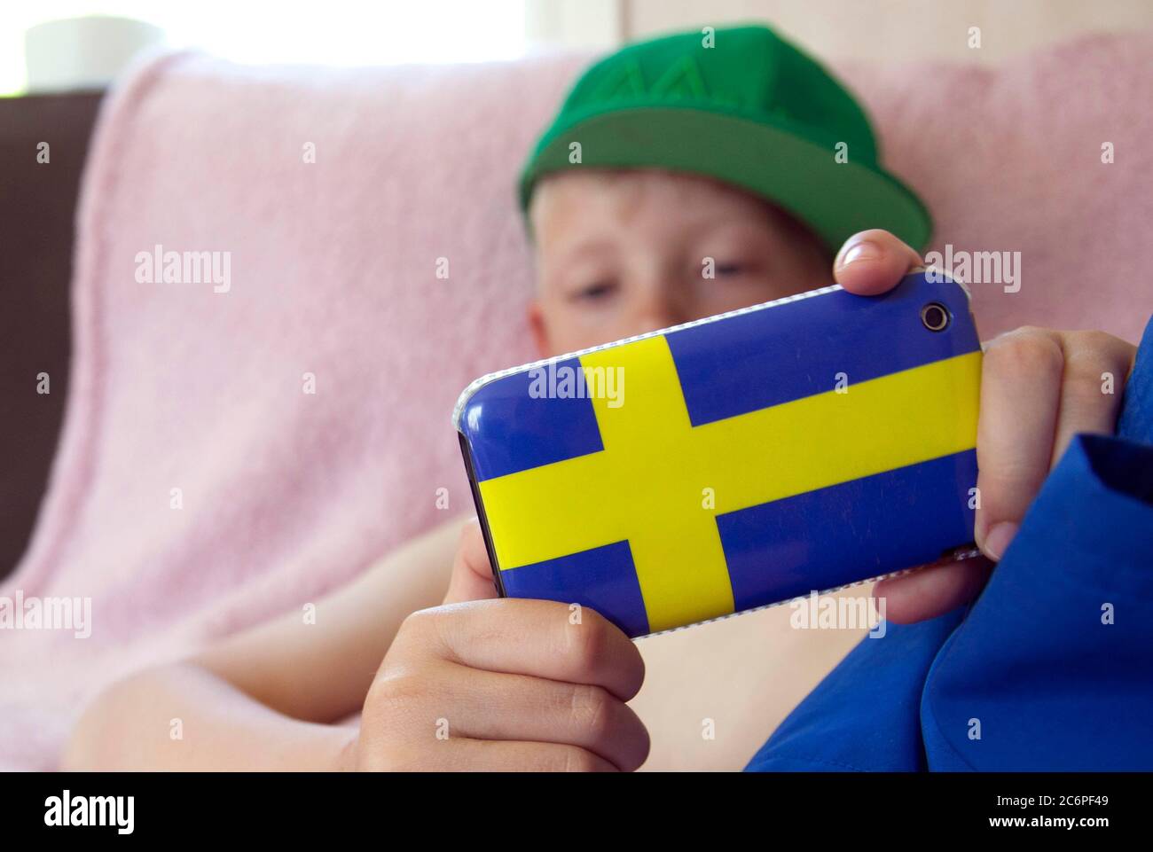 Ein kleiner Kerl, der mit seinem Handy im Internet surft, mit einer Handyhülle in Form der schwedischen Flagge. Foto Jeppe Gustafsson Stockfoto