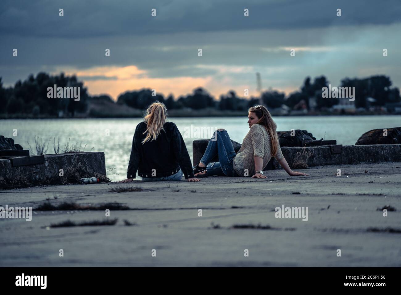 10-07-2020 Riga, Lettland Frau träumt vom Urlaub. Ruhe Entspannung und Hobby. Verbringen Sie Freizeit für sich. Mädchen sitzen auf grünem Gras in der Nähe des Flusses. Stockfoto