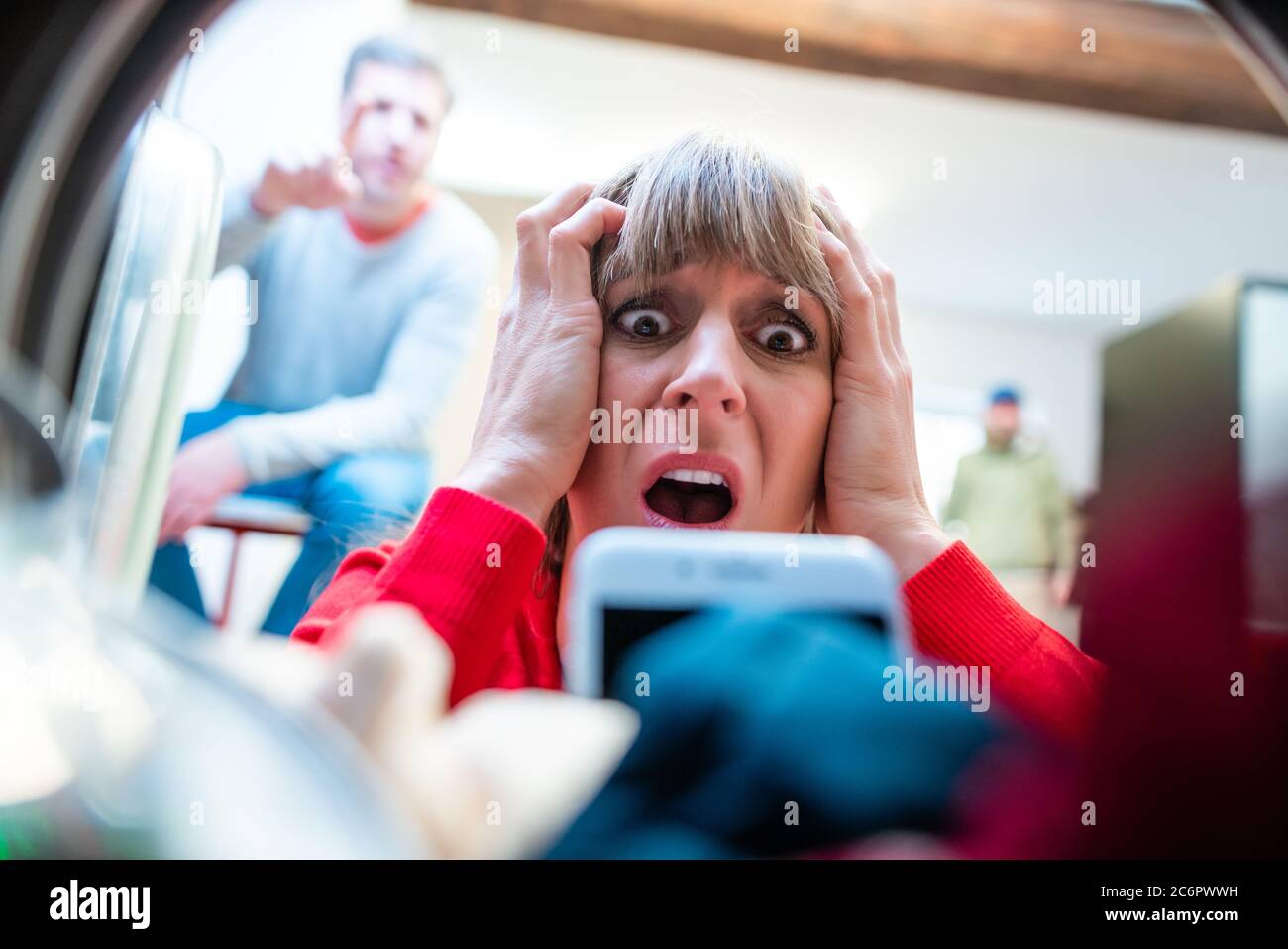 Frau findet ihr Telefon in der Waschtrommel Stockfoto