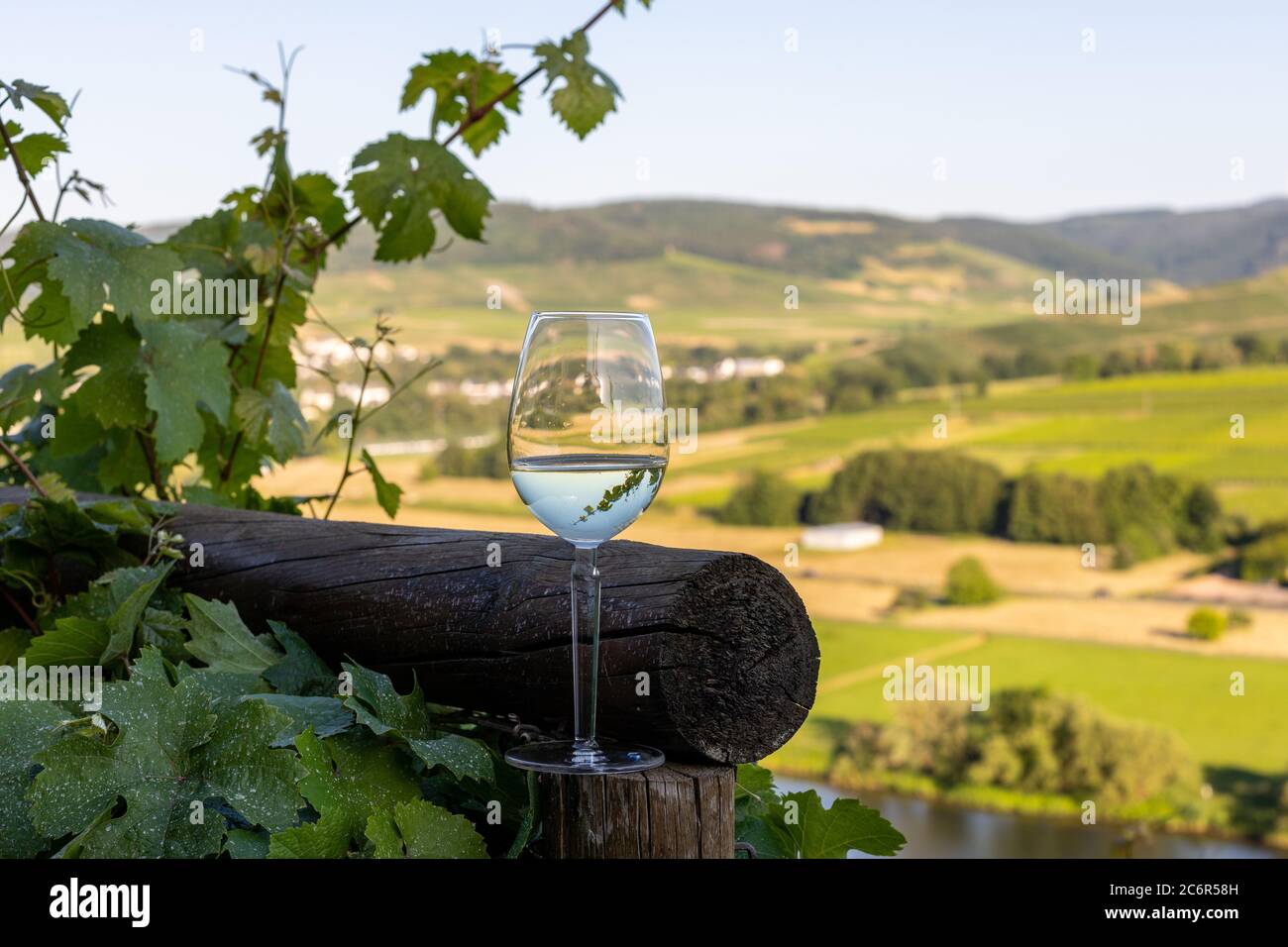 Gefülltes Weinglas neben Holzbalken und Tal der Mosel im Hintergrund  Stockfotografie - Alamy