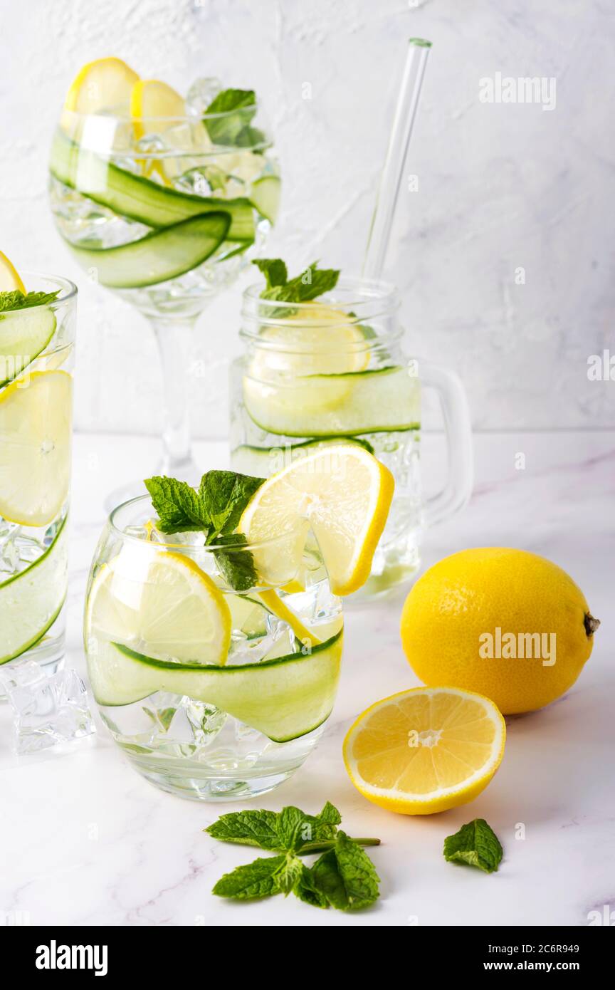 Alkoholgetränk (Gin Tonic Cocktail) in verschiedenen Gläsern mit Zitrone, Gurke, Minzblättern und Eis auf Weiß. Eisgetränk mit Zitrone. Stockfoto