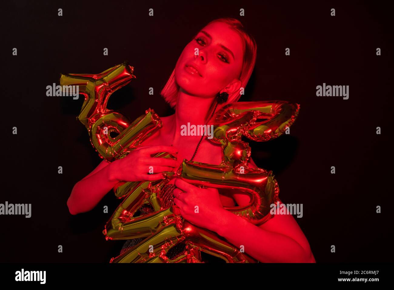 Junge wunderschöne Frau mit Brief geformten Ballons, während Sie auf Ihrem Geburtstag vor schwarzem Hintergrund gratuliert Stockfoto