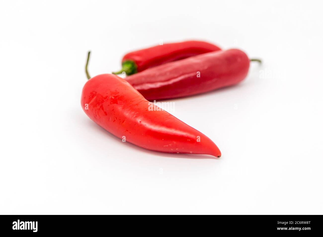 Rote Chilis vor weißem Hintergrund, mit geringer Schärfentiefe Stockfoto