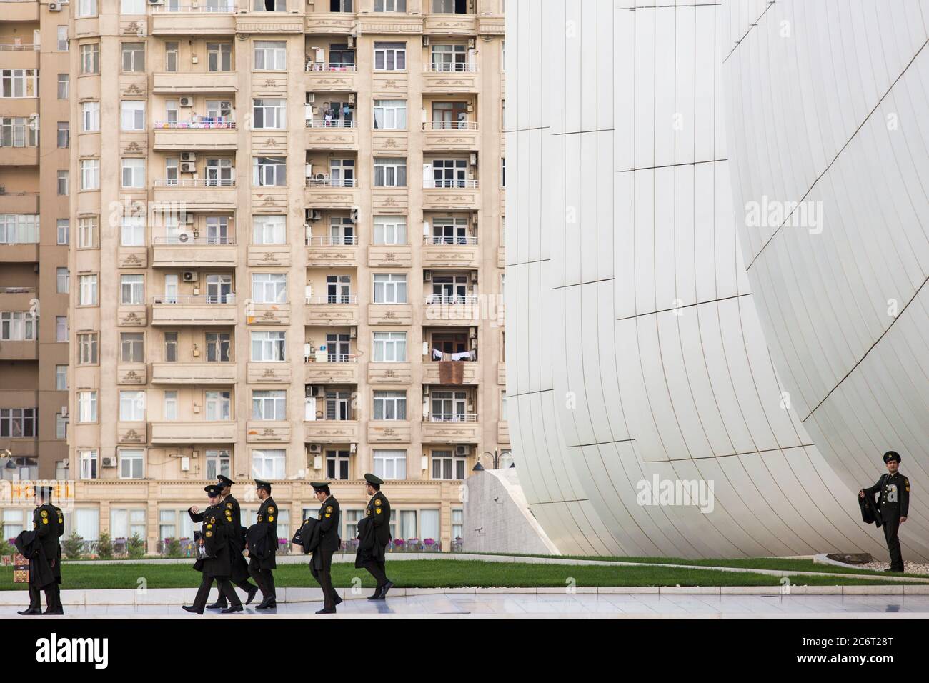 Soldaten gehen an der Front des Heydar Aliyev Zentrums vorbei, das von Zaha Hadid entworfen wurde und das Herzstück der modernen Architektur in Baku Aserbaidschan ist Stockfoto