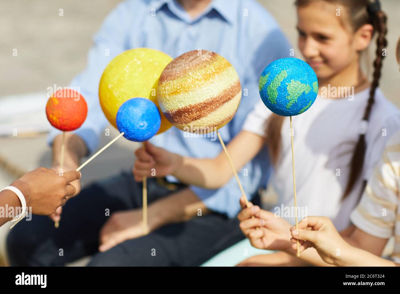 Nahaufnahme einer Gruppe von Kindern, die Modellplaneten halten, während sie im Freien Astronomie-Unterricht im Sonnenlicht genießen, Raum kopieren Stockfoto