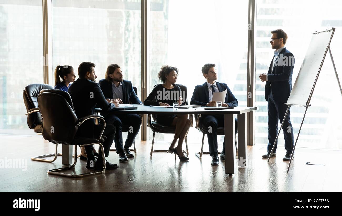 Motivierte junge gemischte Rennen Geschäftsleute hören auf männlichen Sprecher. Stockfoto