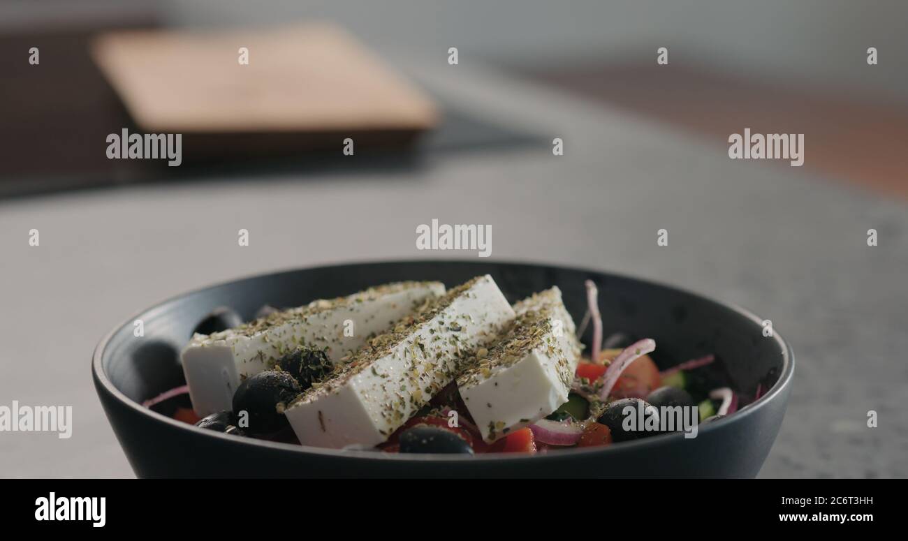 griechischer Salat in schwarzer Schüssel auf Küchenarbeitspe Stockfoto