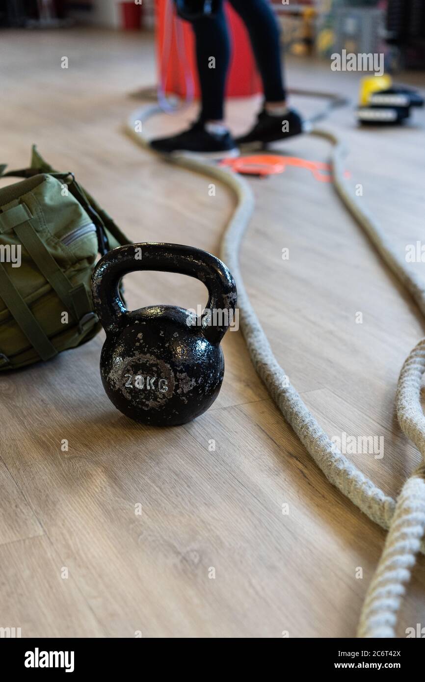 Fitnessgeräte für Boot Camp und trainieren mit Wasserkocher Glocke, Seil, Sandsack in Fitnessraum Halle auf dem Boden. Beine des Dozenten im Hintergrund. Vertikale Aufnahme. Stockfoto