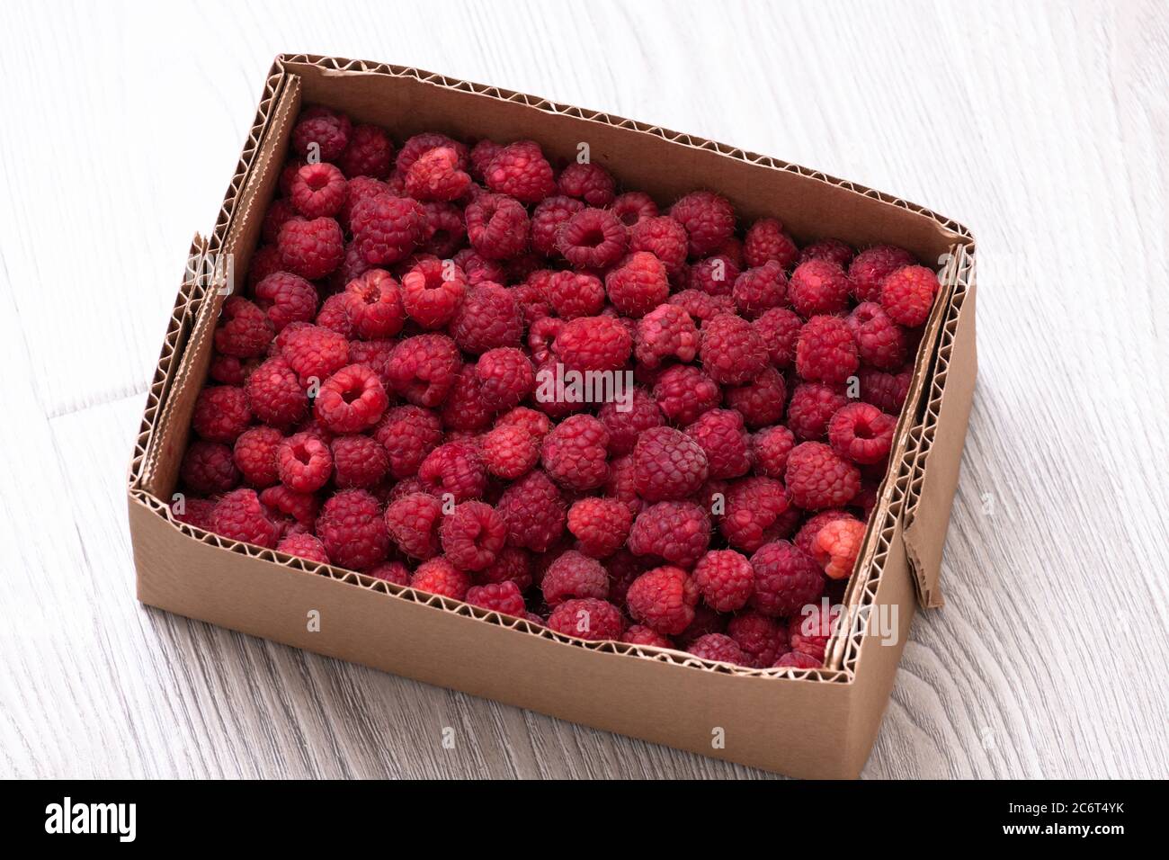 Reife Himbeeren im Karton auf weißem Hintergrund Stockfoto