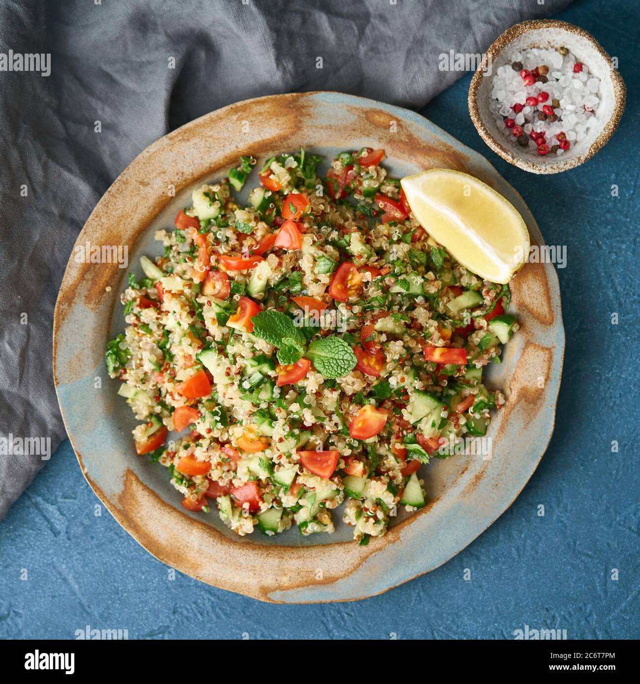 Tabbouleh-Salat mit Quinoa. Östliche Küche mit Gemüse-Mix auf dunklem Tisch, vegane Ernährung. Draufsicht Stockfoto
