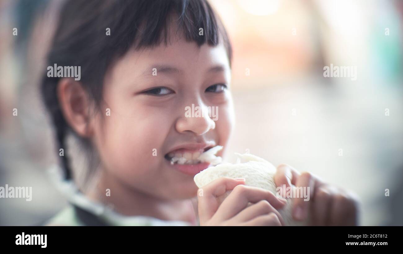 Asiatische Kind Mädchen essen etwas Brot mit Lächeln und glücklich Stockfoto
