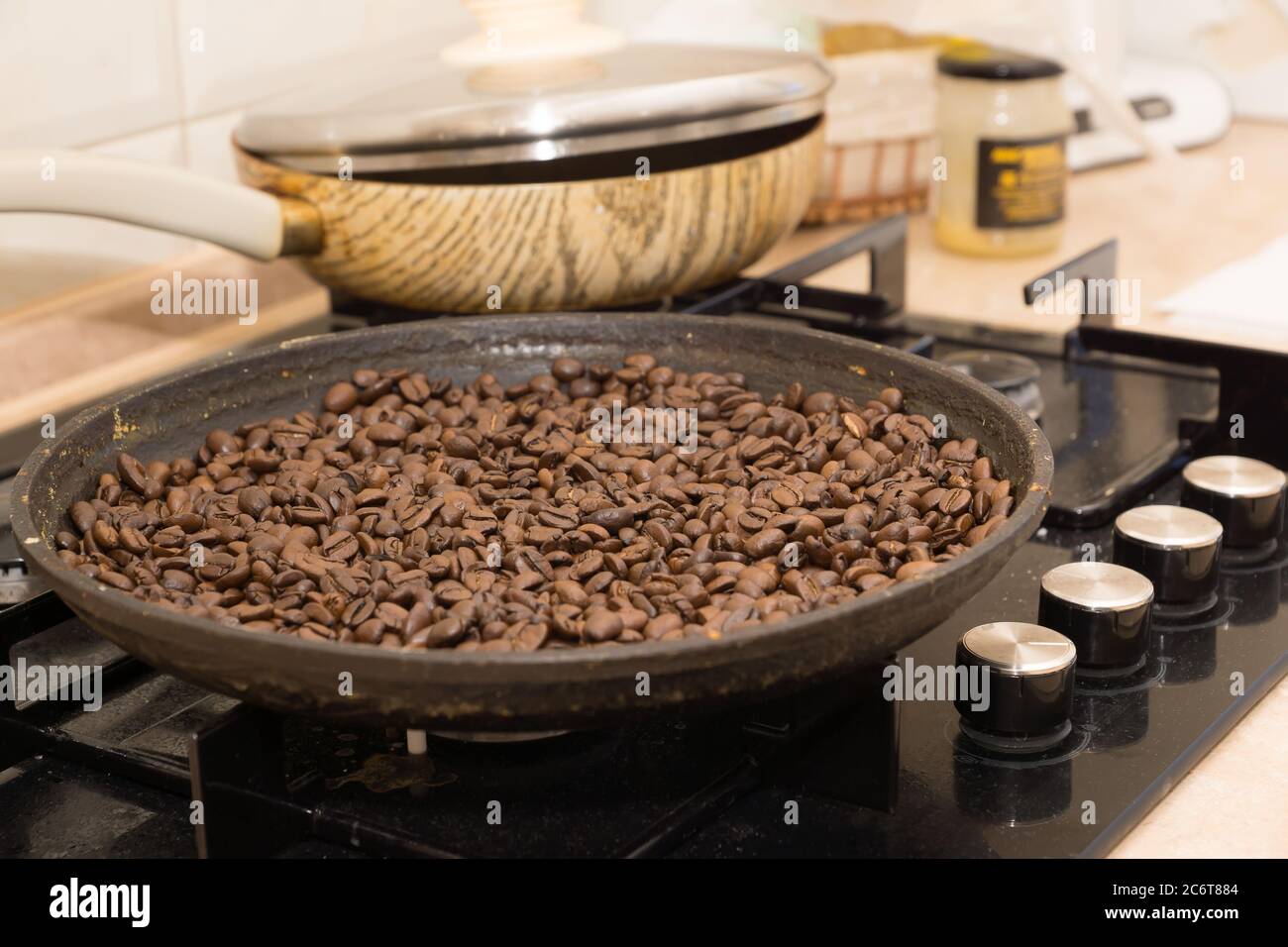 Frisch geröstete Kaffeebohnen auf einem Tisch und einer Pfanne Stockfoto