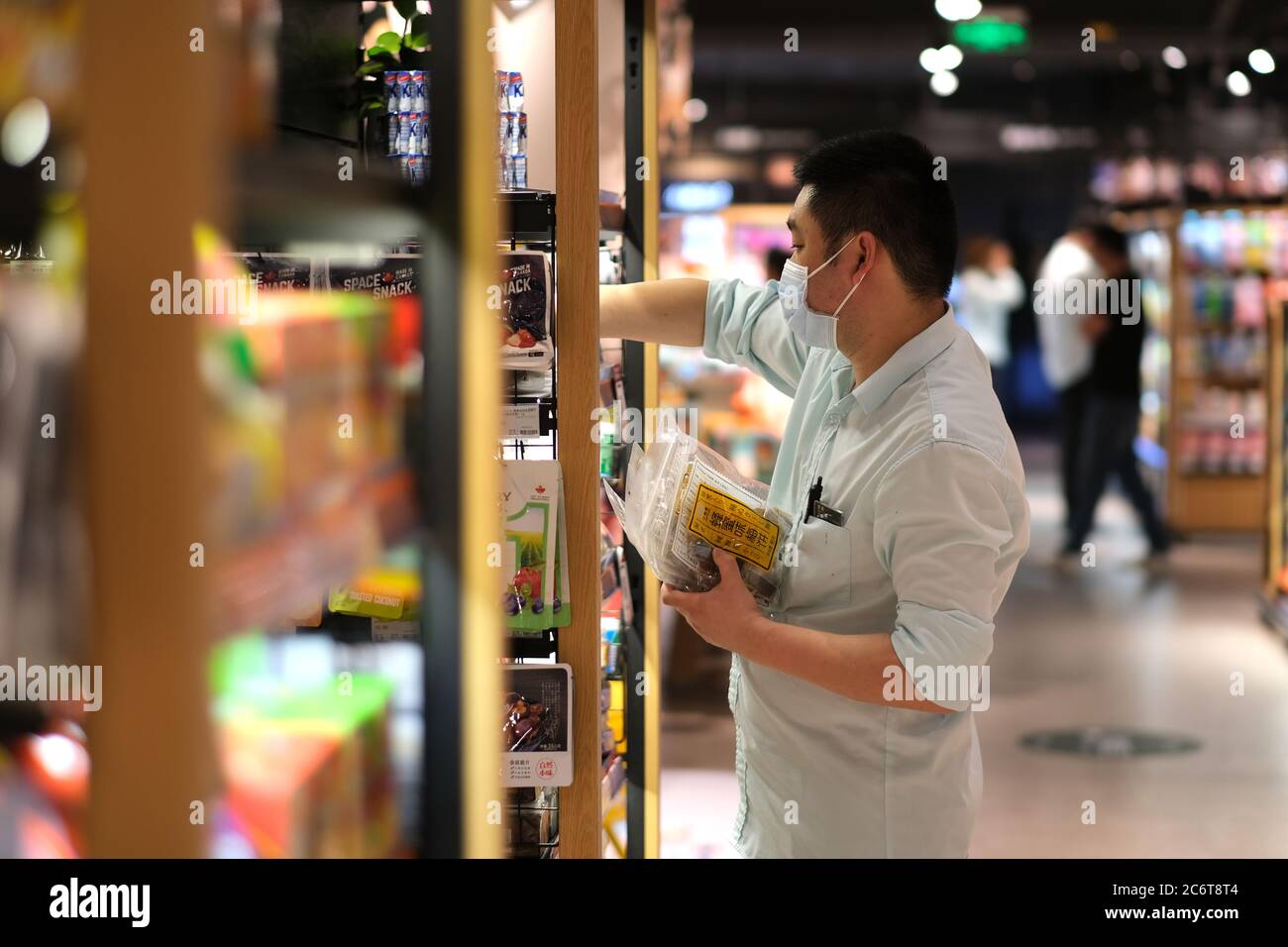 Supermarkt Angestellte Einstellung Lebensmittel im Regal, trägt Gesichtsmaske covid-19 Coronavirus zu vermeiden Stockfoto