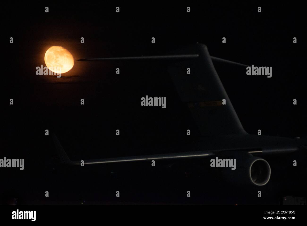 Ein Flügel und Düsentriebwerk aus einer C-17 bei Nacht mit einem Mond im Hintergrund Stockfoto