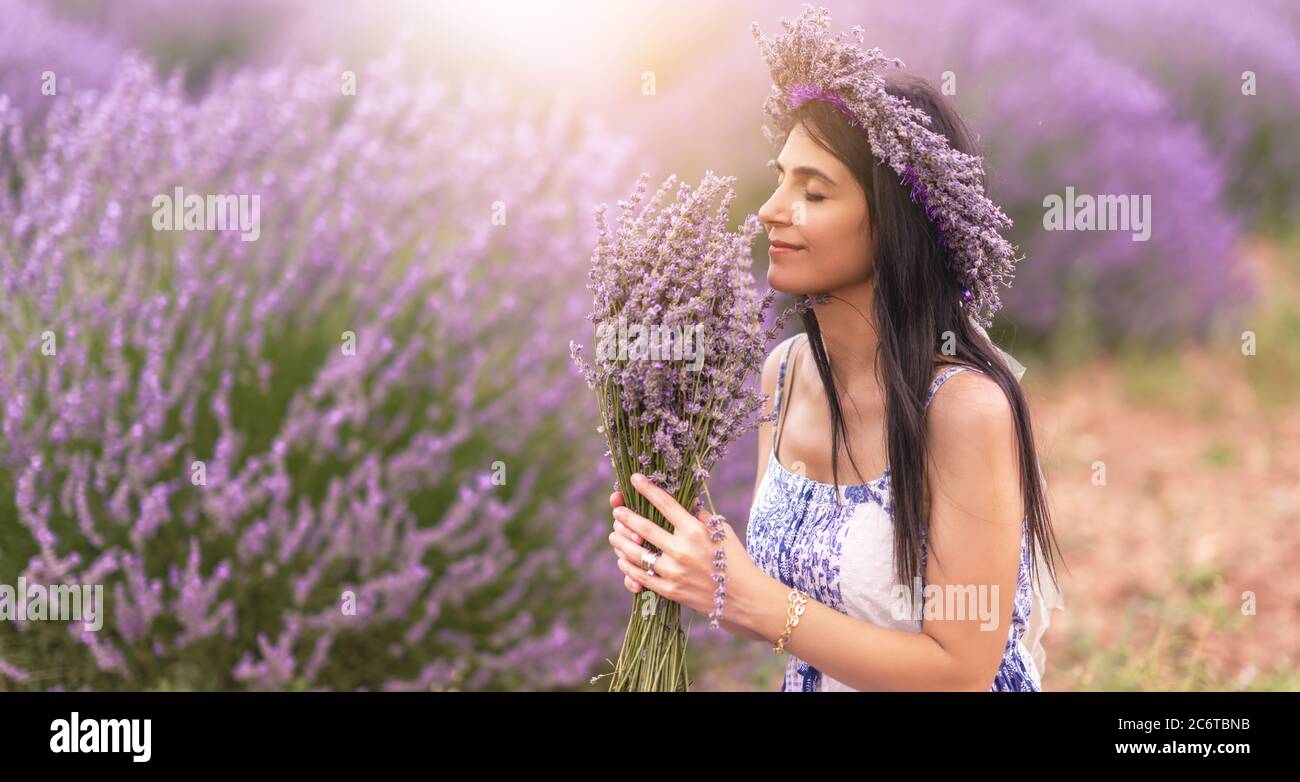 Junge Frau genießt die Aussicht und das Sonnenlicht auf ihrem Gesicht auf einem ländlichen Blumenfeld mit Lavendelblüten. Hochwertige Fotos Stockfoto