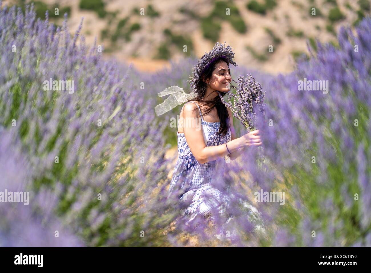 Junge Frau genießt die Aussicht und das Sonnenlicht auf ihrem Gesicht auf einem ländlichen Blumenfeld mit Lavendelblüten. Hochwertige Fotos Stockfoto