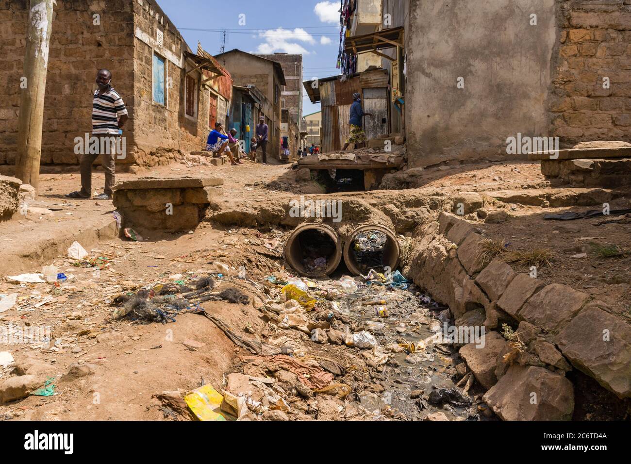 Ein offener Abwasserkanal, der neben einer Feldgasse mit Bewohnern in der Nähe, dem Korogocho Slum, Kenia, Ostafrika, mit Müll gefüllt ist Stockfoto