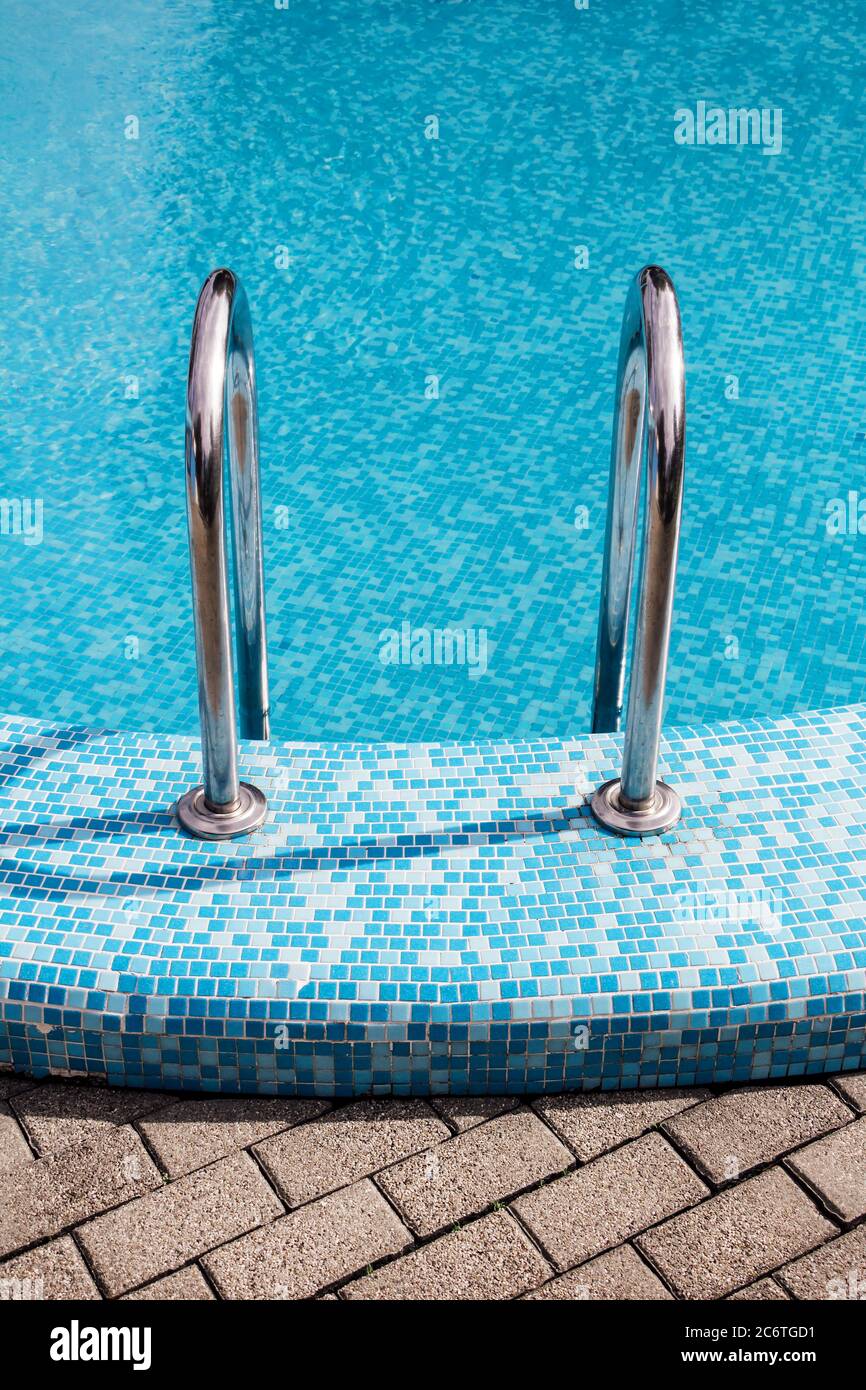 Swimmingpool mit Metalltreppe und wunderschönes entspannendes blaues Wasser Für den Hintergrund Stockfoto