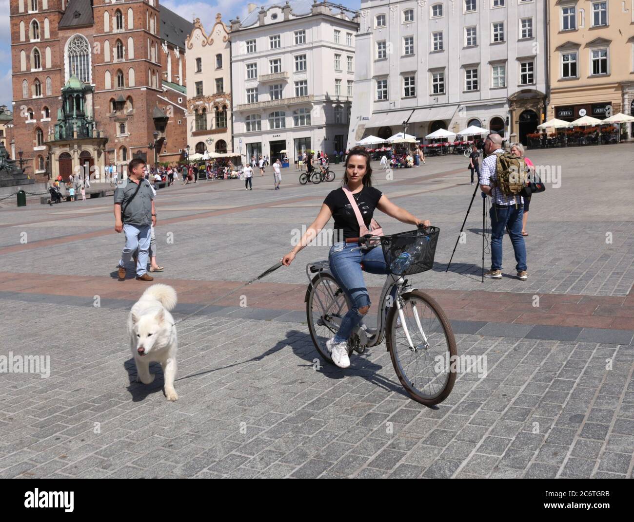 Krakau. Krakau. Polen. Junge Frau, die Fahrrad fährt und gleichzeitig mit dem Hund läuft. Stockfoto
