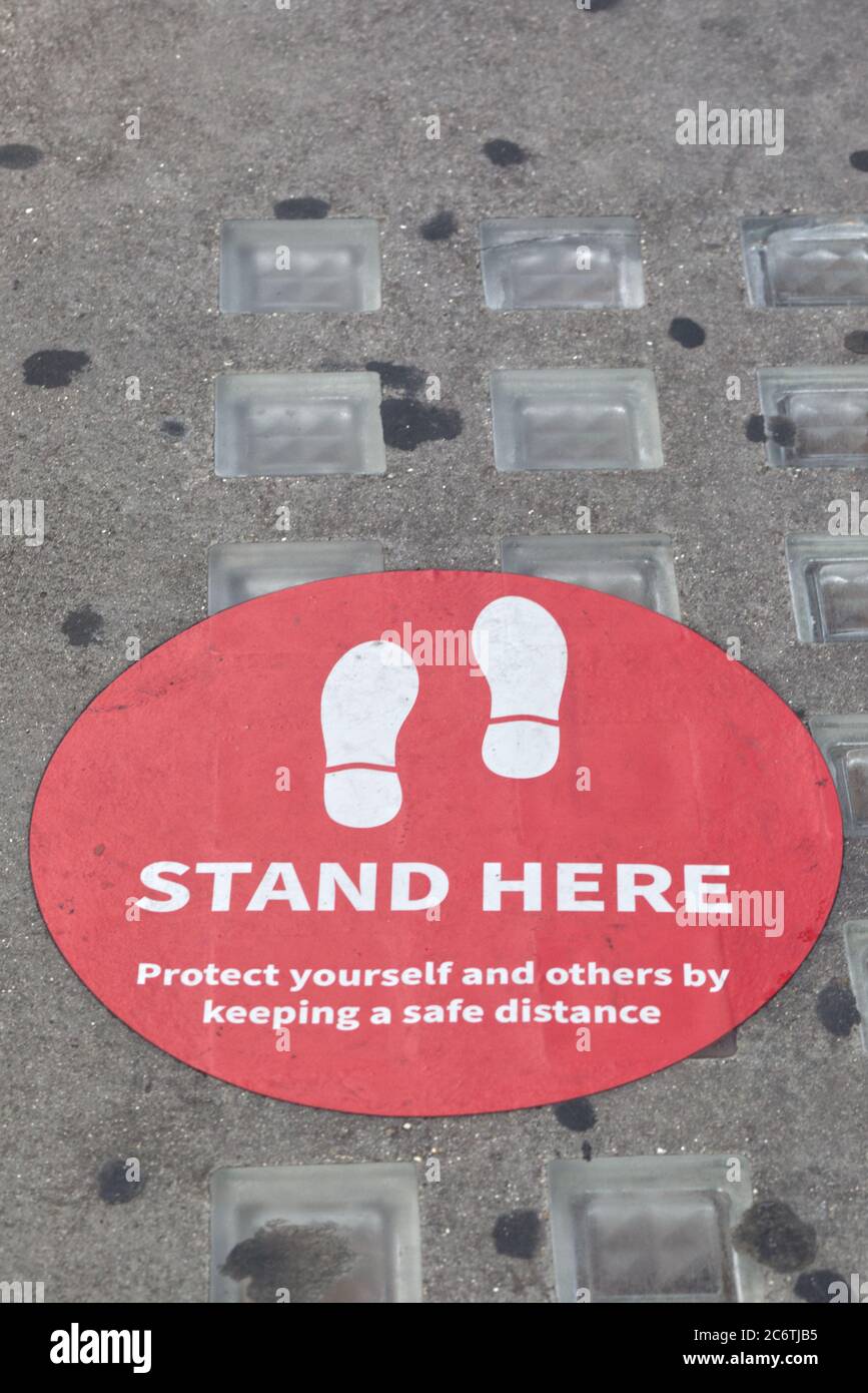 Stehen Sie hier, schützen Sie sich Schild auf dem Boden vor den Geschäften in London Stockfoto
