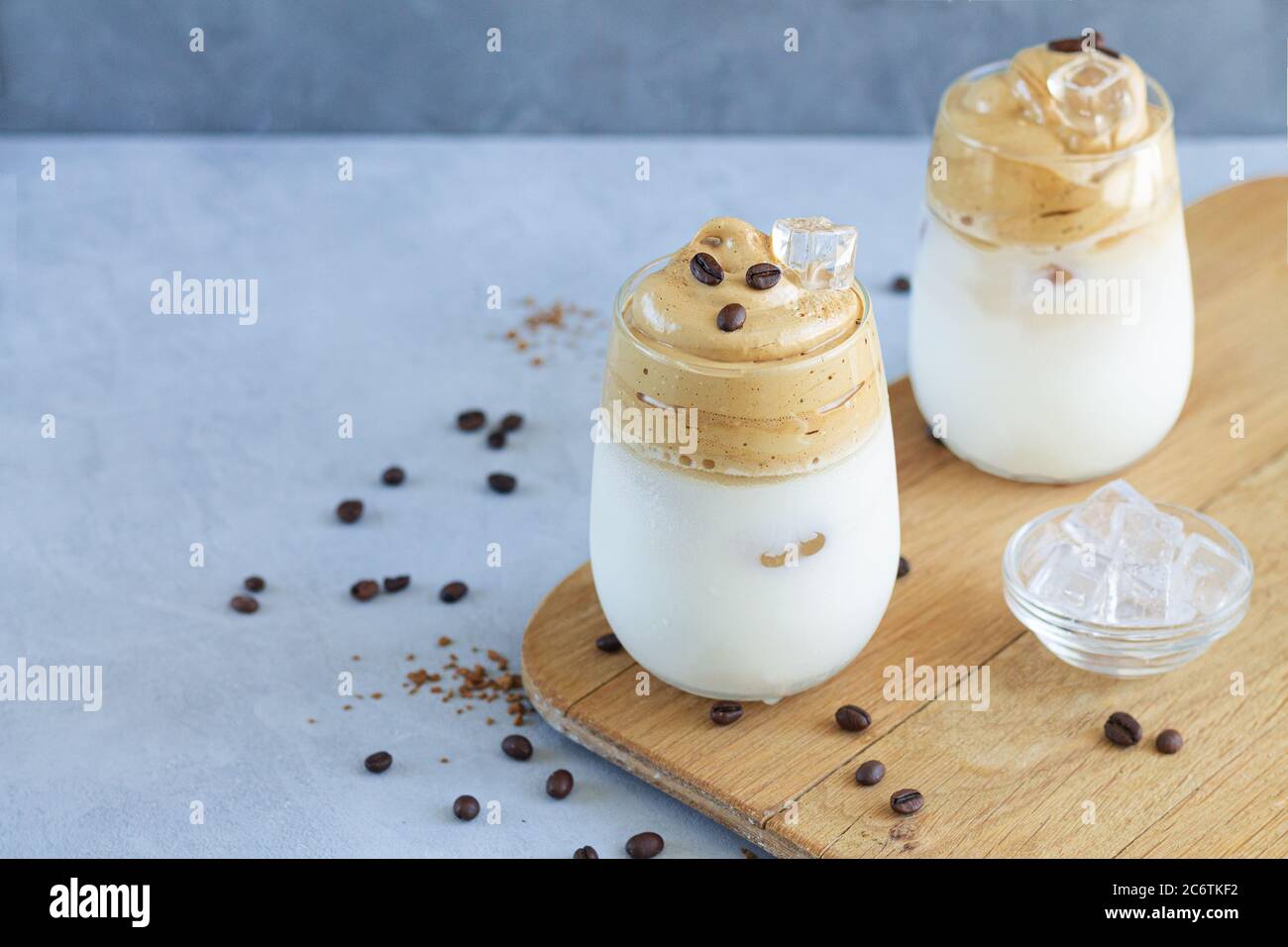 Zwei Gläser kalten Dalgona Kaffee mit Eiswürfeln auf Holzbrett mit Platz für Ihren Text Stockfoto