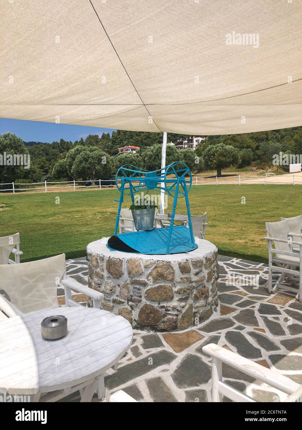 Wasserbrunnen mit Riemenscheibe und Eimer in einem Garten an einem Sommertag Stockfoto