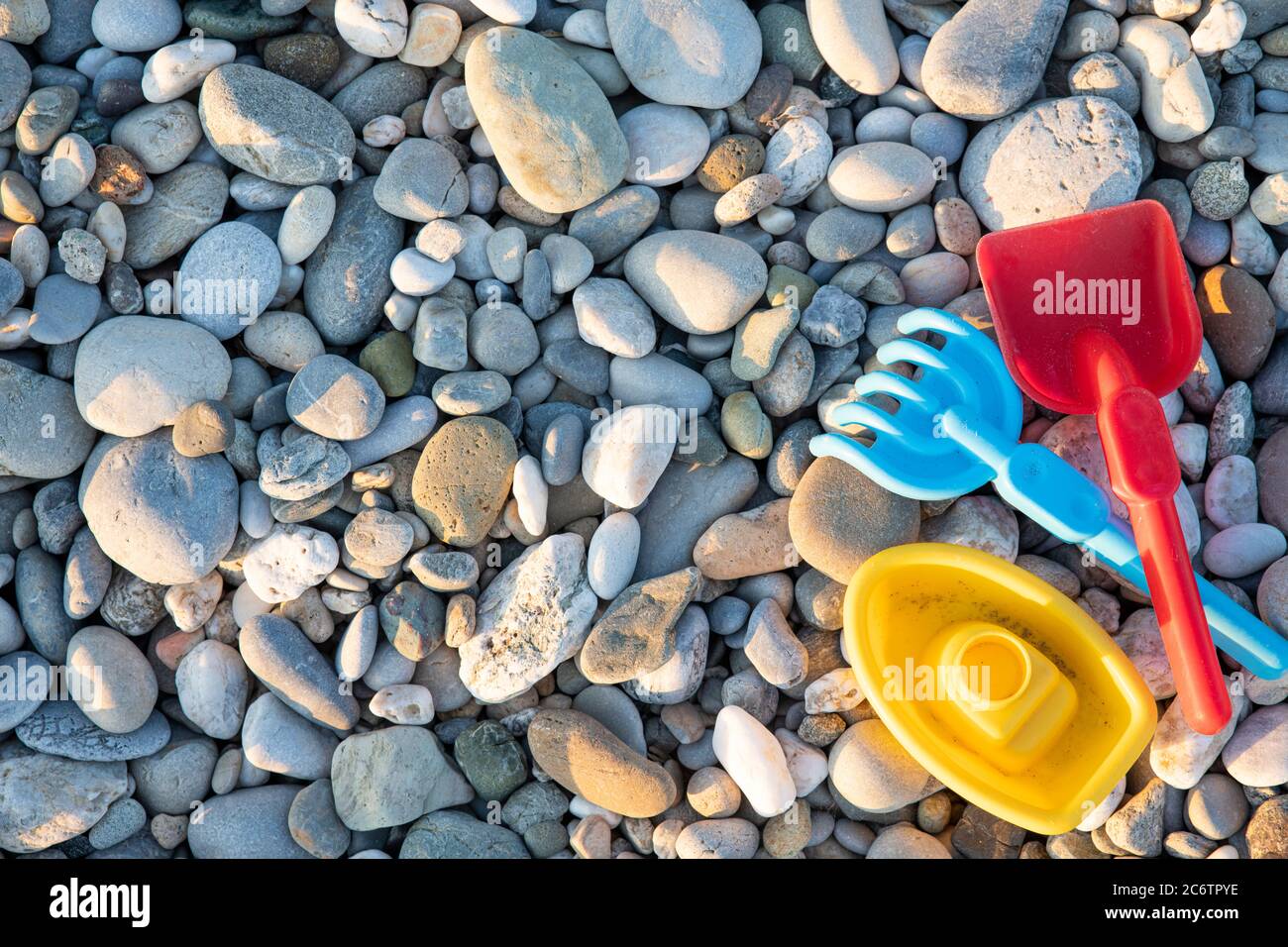 Bunte Kunststoff Spielzeug für Kinder auf einem Stein Strand Hintergrund, Sommerzeit Stockfoto