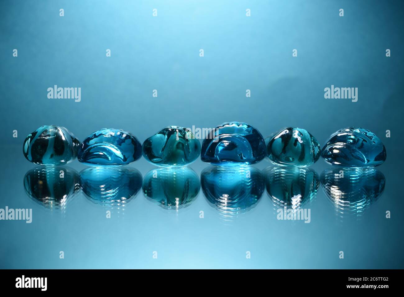 Blaue dekorative Glassteine auf blauem Hintergrund. Stockfoto