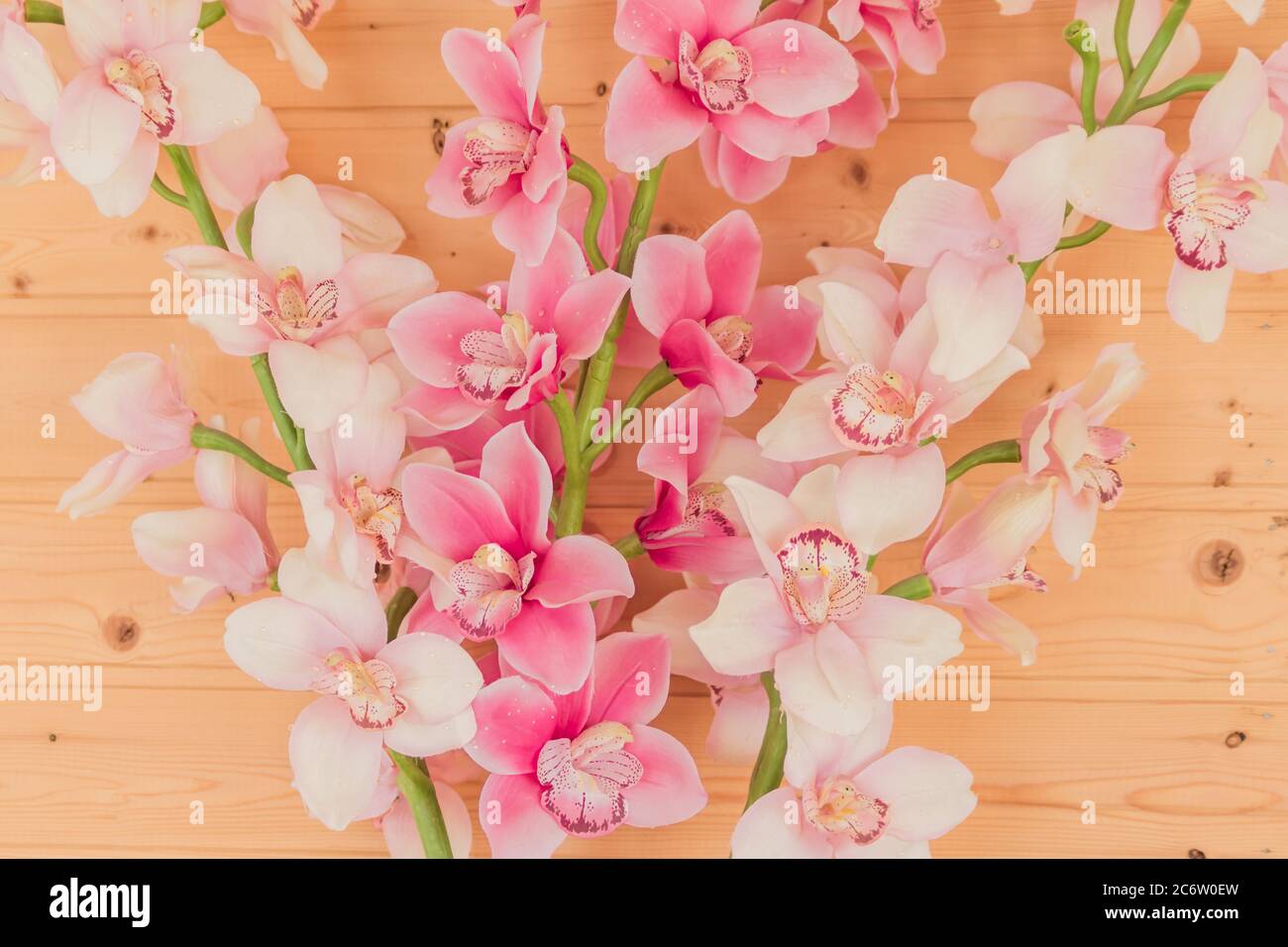 Bündel von künstlichen blühenden Orchideenblumen auf hölzernen Hintergrund. Inneneinrichtung. Stockfoto