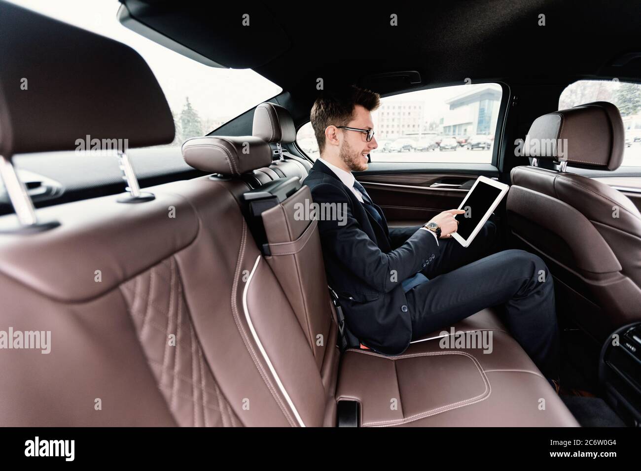 Junger Geschäftsmann mit seinem digitalen Tablet in Luxuswagen Stockfoto