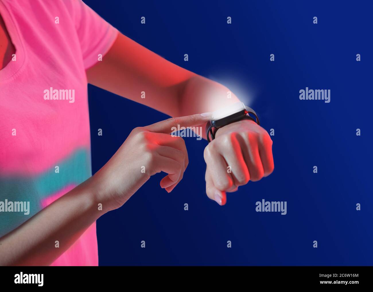 Moderne Gadgets für Millennials. Frau verwendet Smart-Uhr mit Leuchtbildschirm auf blauem Hintergrund Stockfoto