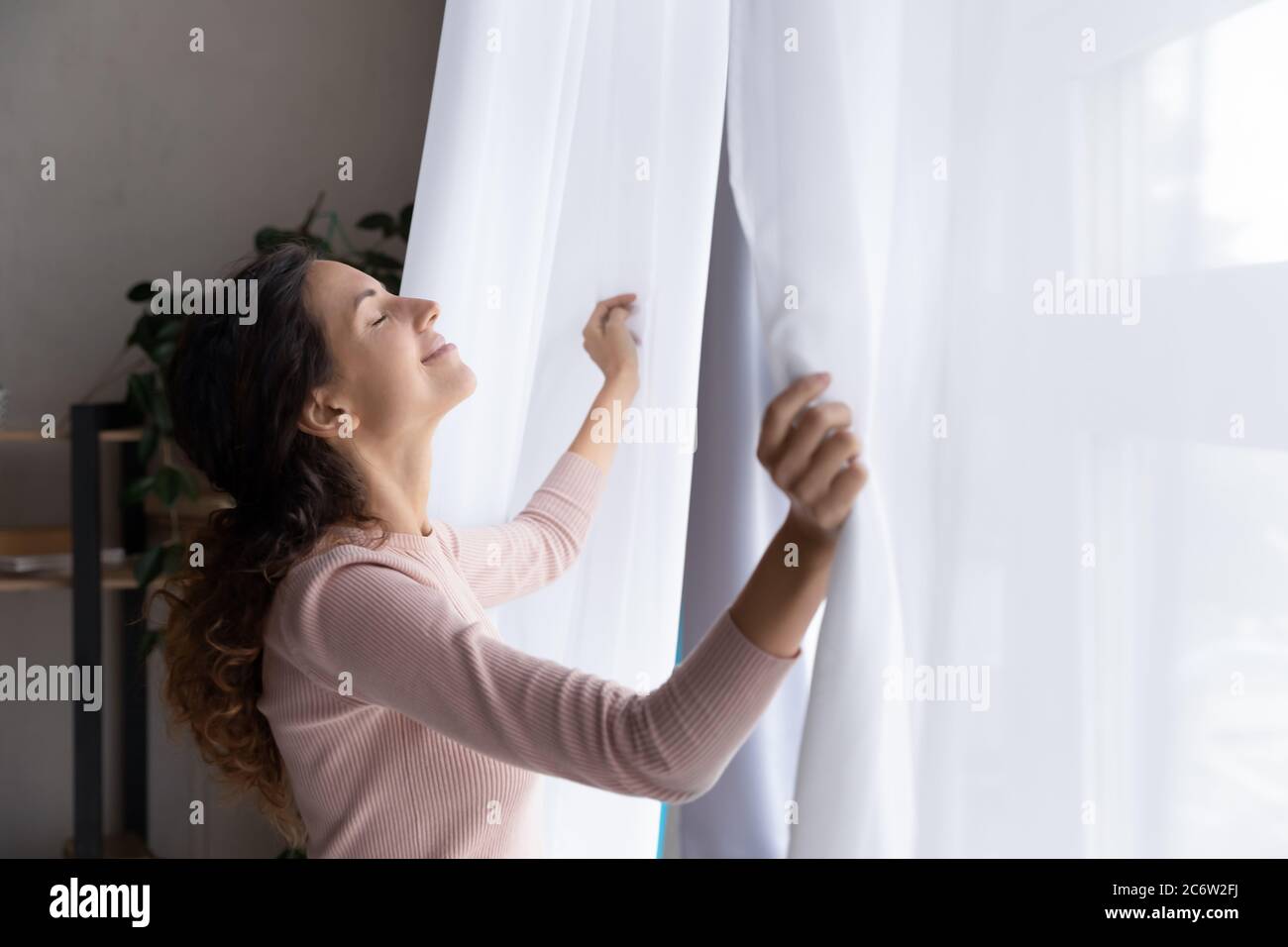 Glückliche junge Frau offene Vorhänge begrüßen neuen Tag Stockfoto