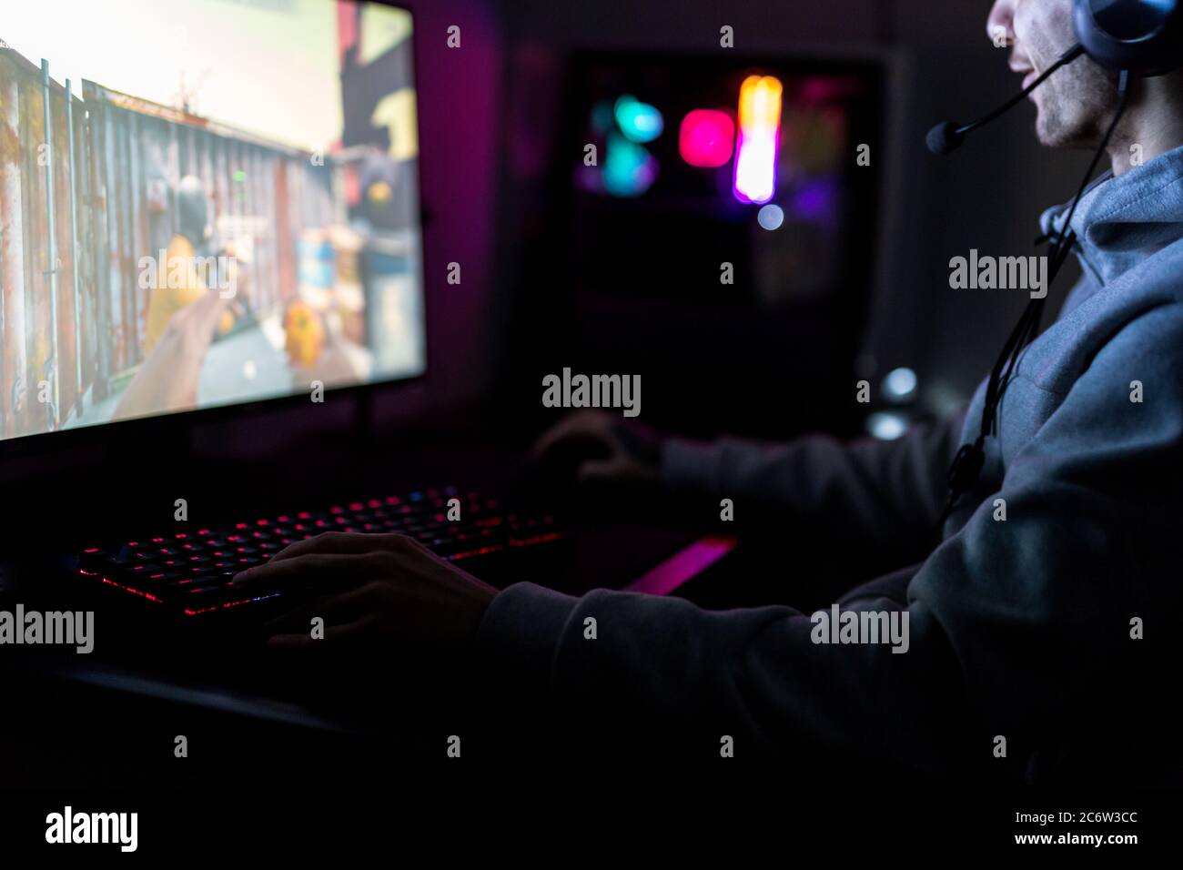 Professionelle Gamer oder Streamer spielen Ego-Shooter Online-Videospiel auf einem benutzerdefinierten Gaming-PC. Er trägt ein Headset und spielt auf einem Stockfoto