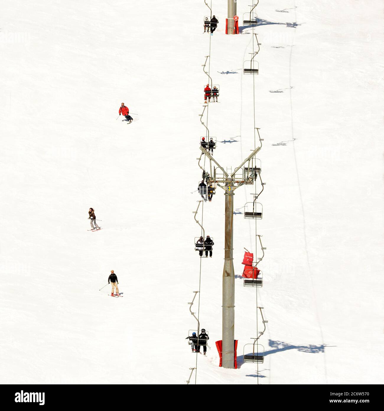 Das schneebedeckte Skigebiet bietet Sessellifte und Skifahrer, die bei hellem Tageslicht Winteraktivitäten genießen, Auvergne-Rhone-Alpes, Frankreich Stockfoto