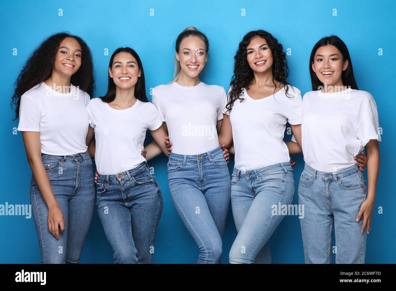 Diverse Mädchen Umarmen Posiert Auf Blauem Hintergrund, Lächelnd Zur Kamera Stockfoto