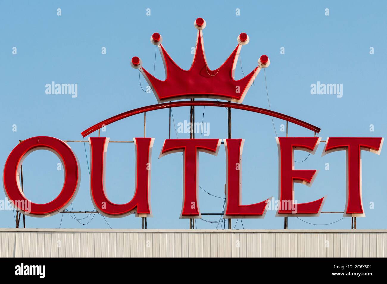 Outlet-Schriftzug und Royal Crown Red LED-Neon-Logo auf dem Dach des Outlet Center-Gebäudes Stockfoto
