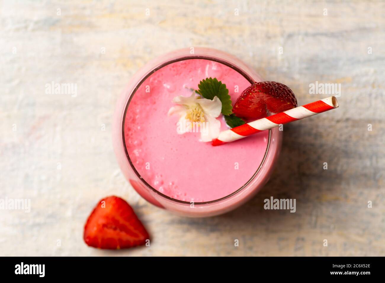 Erdbeer-Smoothie in einem Glas mit weißer Blumenplatte verziert Stockfoto