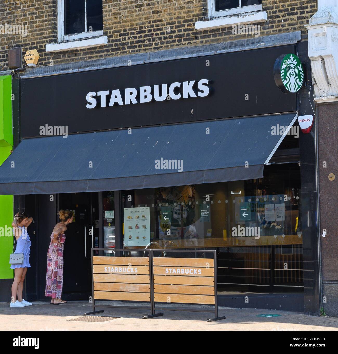 Bromley (Großraum London), Kent, Großbritannien. Starbucks Cafe in der Bromley High Street. Zeigt den Starbucks Store und das Logo mit zwei Gästen, die teilnehmen möchten. Stockfoto