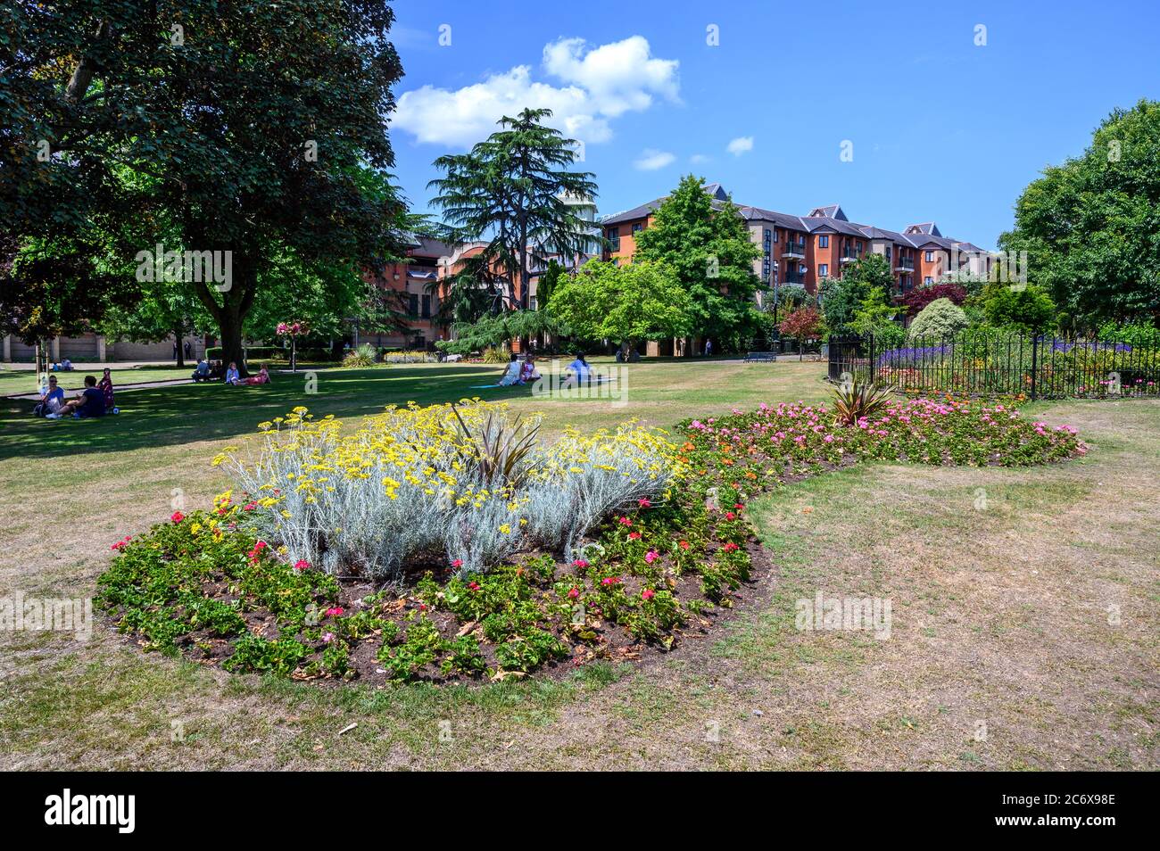 Bromley (Großraum London), Kent, Großbritannien. Queens Gardens in der Nähe des Einkaufszentrums Glades in Bromley. Hübsche Blumenbeete und Leute, die auf dem Rasen sitzen. Stockfoto