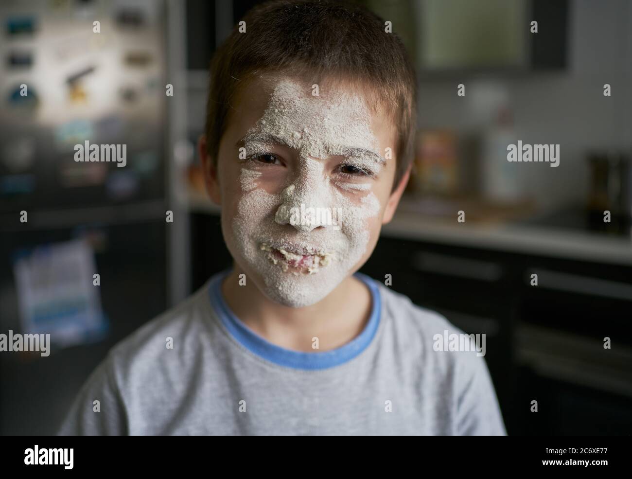 Beleidigt unglücklichen Jungen mit Gesicht mit Mehl in der Küche bedeckt Stockfoto