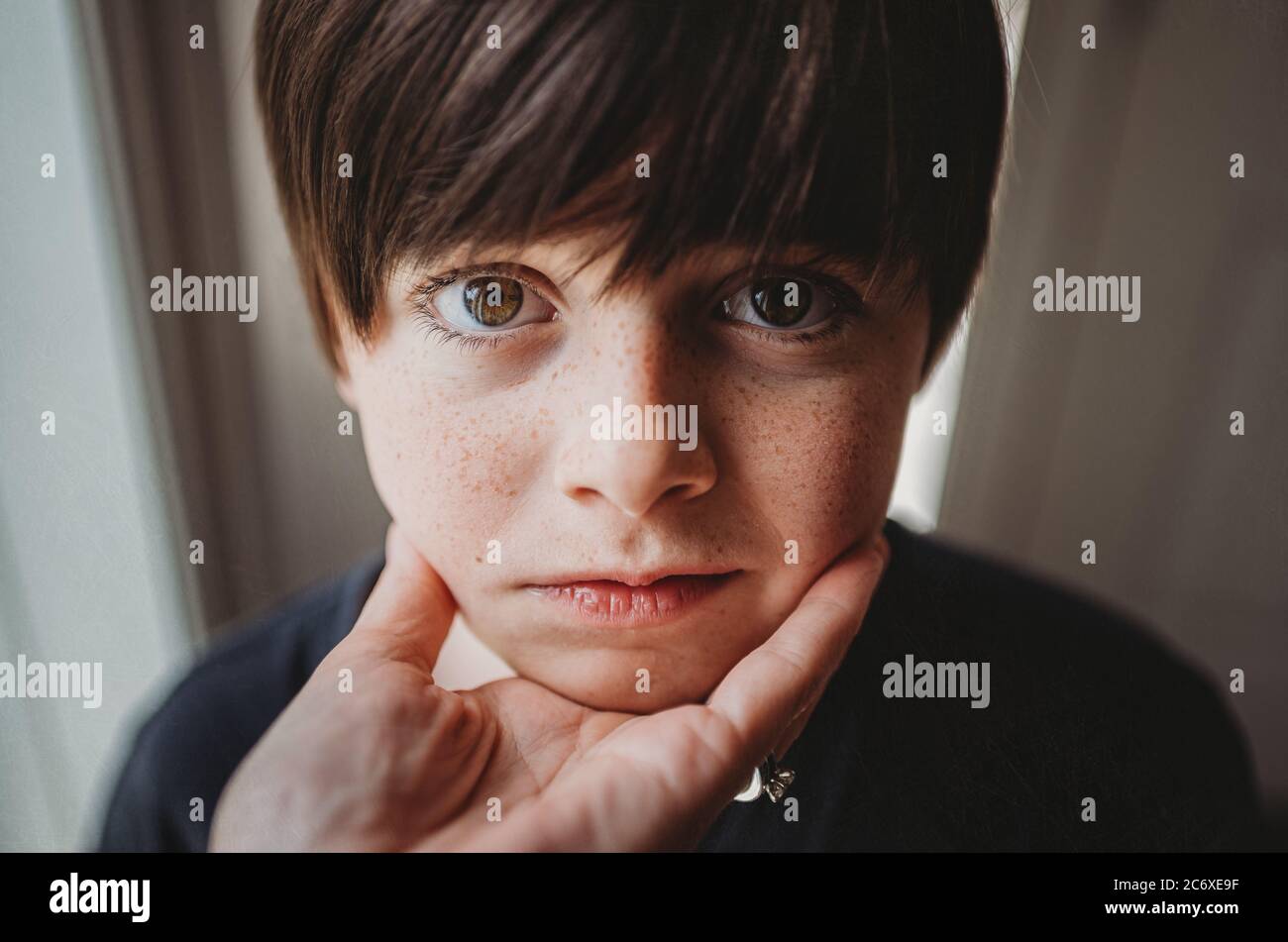 Nahaufnahme des Gesichts des Jungen, das an einer Hand unter seinem Kinn gehalten wird. Stockfoto