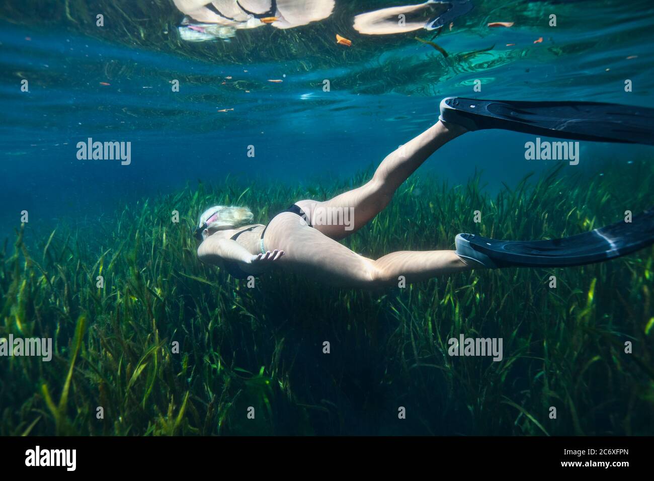 Unterwasserfoto einer Frau, die im kristallklaren Wasser schnorchelt und über Seegras schwimmend ist Stockfoto